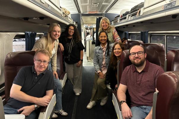 A group of men and women pose in the business car on board an Amtrak train
