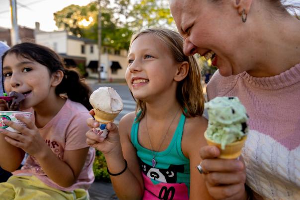 A woman and two young girls eat ice cream cones outside