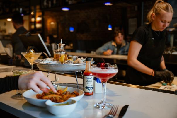 A plate of food at Jax with someone shucking oysters in the background
