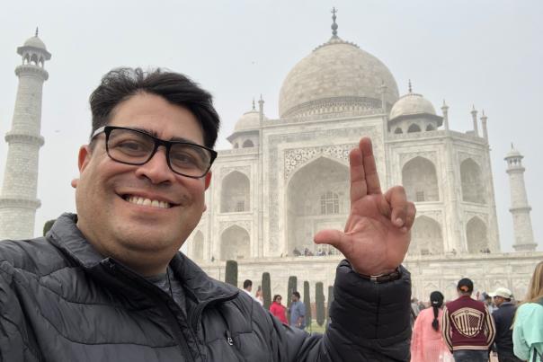 Dr. Daniel Guerrero poses with his "states up" Texas State University hand gesture in front of the Taj Mahal