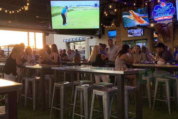 Big screen TV and patrons sitting at high table tops at Little Woodrow's Sports Bar