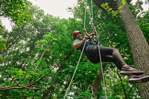 Person on a zip line in the woods.