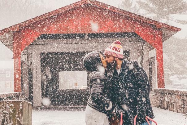 Couple kissing with dog in front of Bogert's Bridge in Allentown, PA while its snowing.