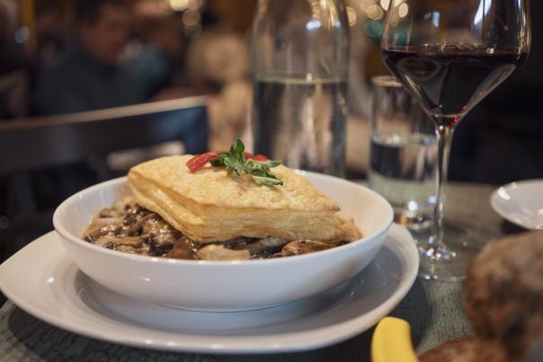 Bowl with puff pastry and wine glass on table top.