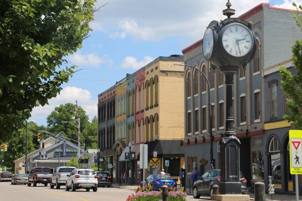 colorful buildings line a street. A clocktower stands at the front of the street.