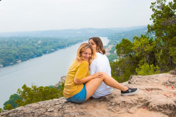 Two woman sitting close atop Mount Bonnell.