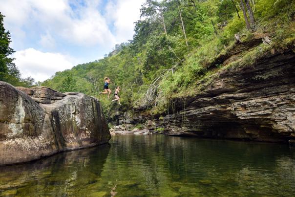 Two People jump of large rock into the North Chickamauga Creek Blue Hole