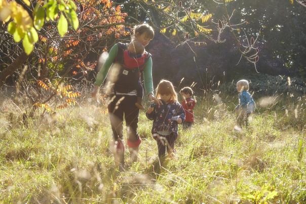 Mother and children walking through long grass and autumn trees