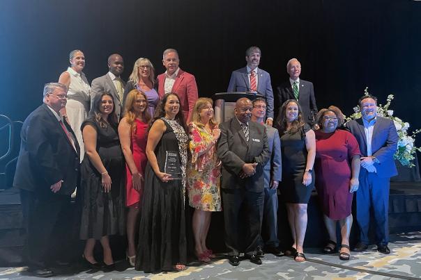 A group of business professionals pose with an award