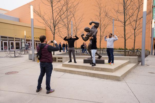Arnold Sports Festival attendees flexing muscles with the Arnold statue outside of the Greater Columbus Convention Center
