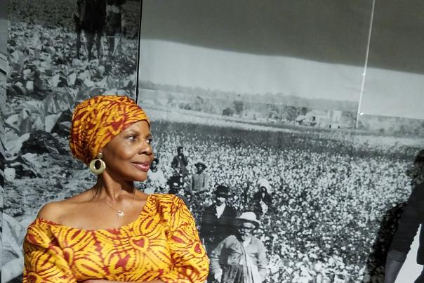 Dr. Kitty Oliver standing in front of a black and white photo at the African American Research Library
