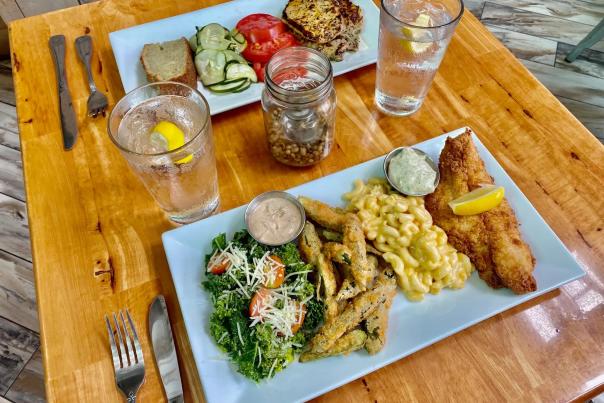 two plates of food on a table - fish, mac and cheese, fries, greens