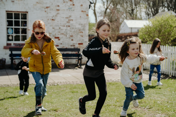 Four children having an egg and spoon race during Easter celebrations.