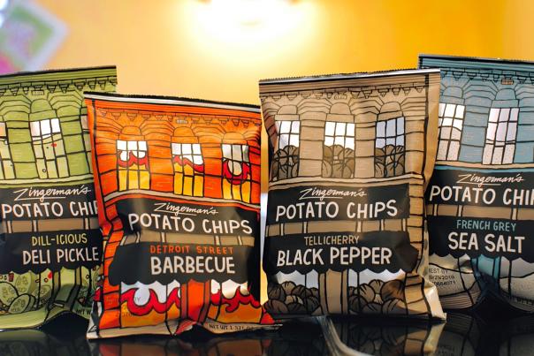 Four bags of potato chips sit on a table.