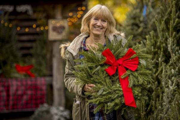 Woman holding wreath with red ribbon on it