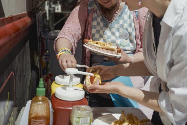 Two people putting ketchup on their hotdogs.