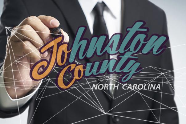 The Johnston County Visitors Bureau logo in front a hand drawing it.