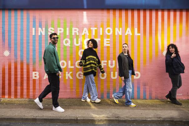 4 people walking in front of street art