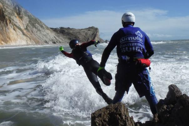 People jumping off rocks, coasteering on the Jurassic Coast in Dorset