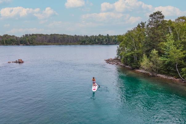 A woman stand up paddle boarding on the St. Marys River in the Upper Peninsula of Michigan.