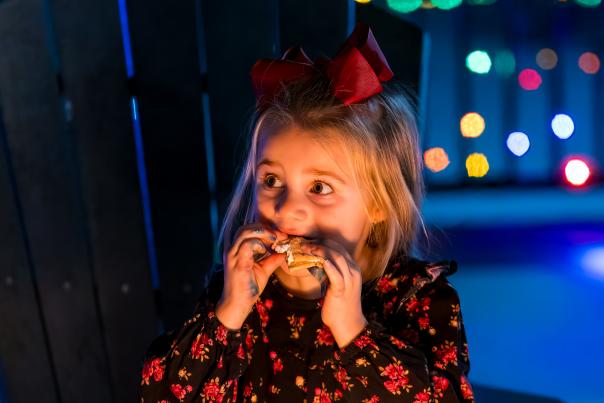 A child enjoys a s'more near a firepit among the glow of Christmas lights at Illumination at Coca-Cola Park in Allentown, PA.
