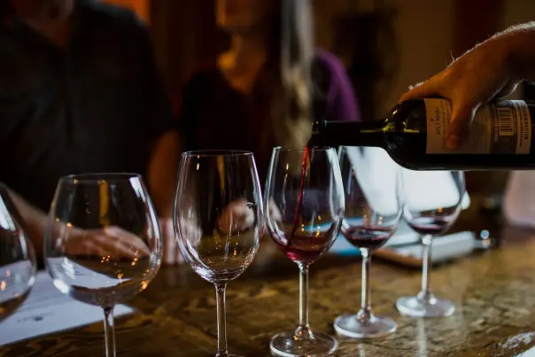 A row of wine glass being filled with red wine.