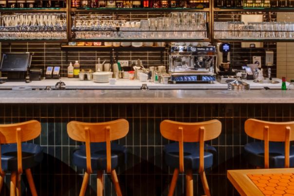Six stools placed in front of a bar at a Pizza Express. There are two tables in the foreground.