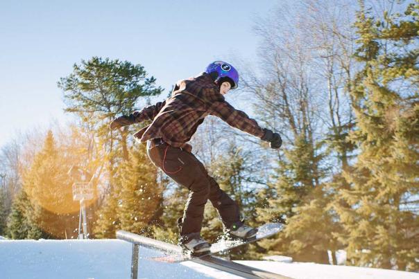 Person snowboarding on a pipe at a ski resort on a sunny day