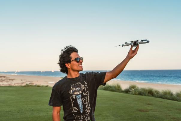 fotografía de adrián montalvo sosteniendo un dron frente a la playa