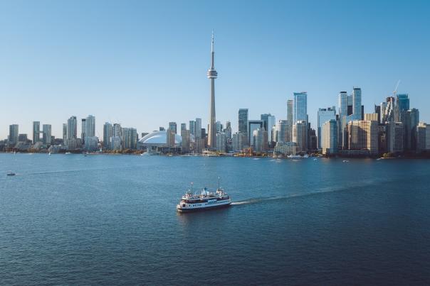 The Toronto skyline seen from Lake Ontario with a ferry passing on the water in front of the CN Tower