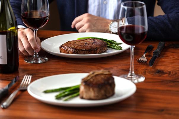 Two plated steaks with asparagus and wine on a table