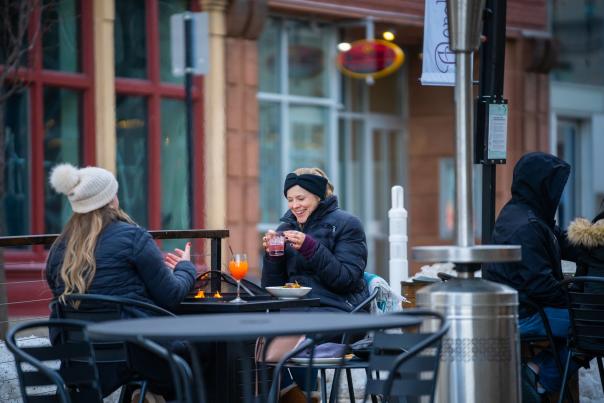 Two women enjoy drinks outdoors in winter