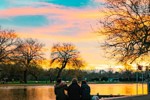 The sun sets over the River Avon as three tourist sit and watch