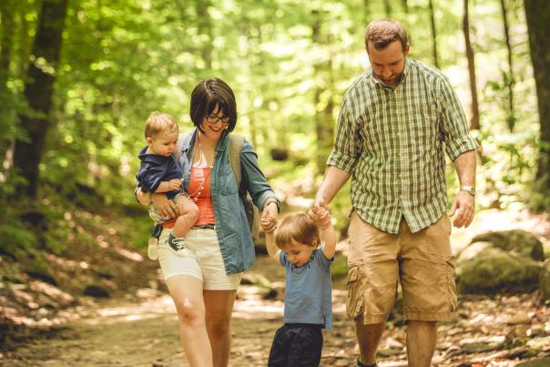 A family of 4 hikes through the woods on an easy trail at Paris Mountain State Park.