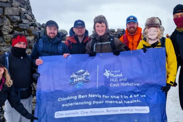 The Humber Mountaineering community stand on top of a snowy mountain holding a HEY mind fundraiser banner.