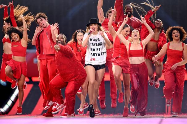 Taylor Swift during the Eras Tour with backup dancers in red clothing