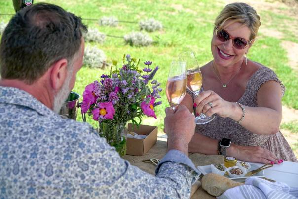 Couple at Hambly Farms celebrating with wine and food, women smiling at husband