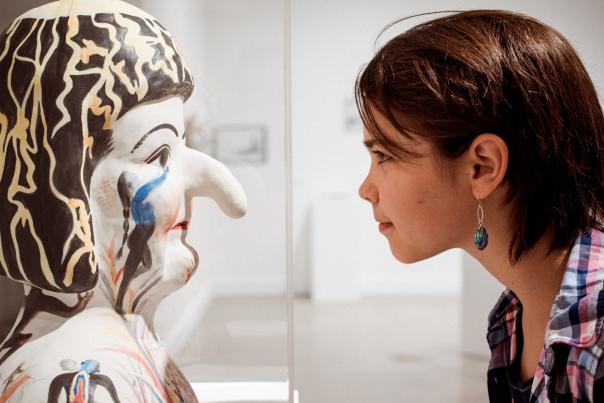 A girl looking at the face of a statue.