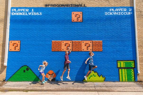 kids jumping in front of mario mural wall