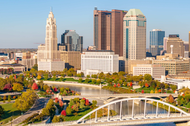 Columbus skyline in the fall. Red and yellow trees surround the Scioto River