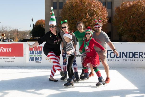 A group of people in christmas clothing on an outdoor ice skating rink