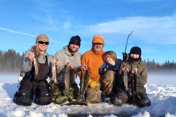 Family showing ice fishing catch in February 2024
