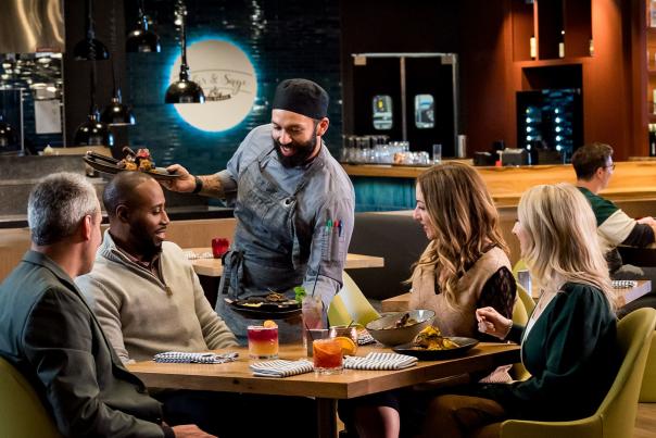 Chef serves a group of diners at Cedar and Sage restaurant in Green Bay.