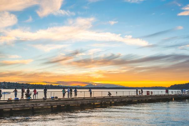 People viewing sunset over Lake Washington on a boardwalk
