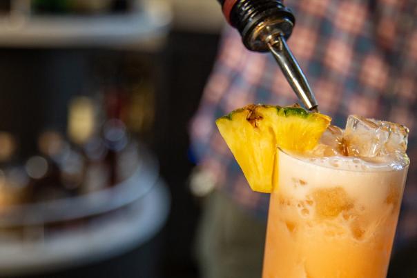 A bartender making a tropical cocktail with pineapple garnish