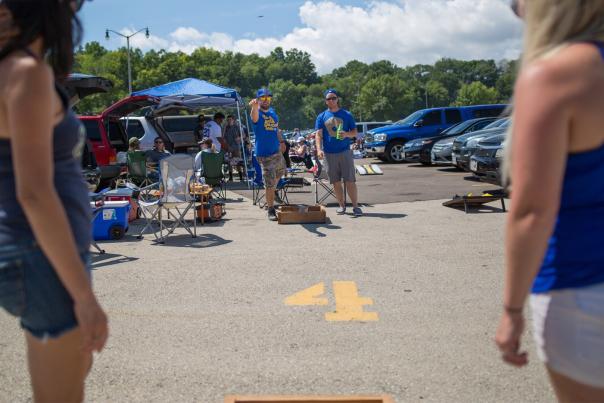 A group of Brewers fans playing a game of corn hole while they tailgate