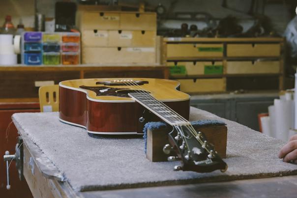 Photograph of an artist's studio with a guitar laid out on a workbench