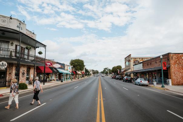 Two older women crossing the street in a small town mainstreet lined with boutiques.