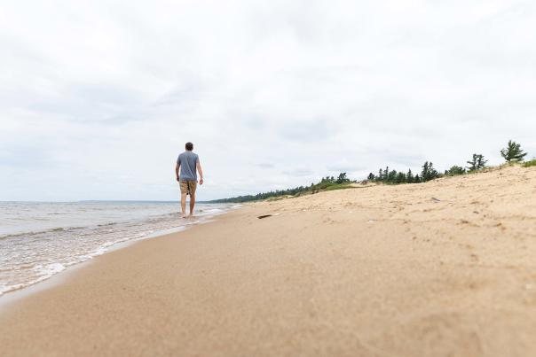 man walking along Lake Michigan beach near US-2 in the Upper Peninsula Michigan