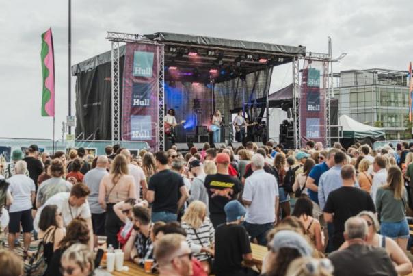 A crowd of people watch a singer on stage near the Deep in Hull for Humber Street Sesh